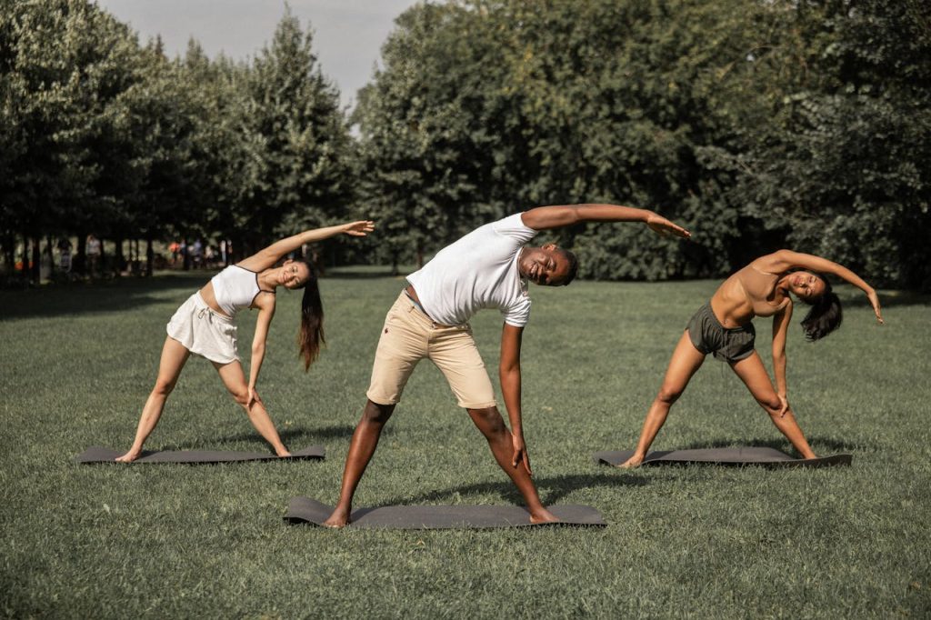 multiracial-people-doing-reverse-triangle-pose-5384538 Group of diverse people in activewear stretching body while practicing Parivrtta Trikonasana in summer park